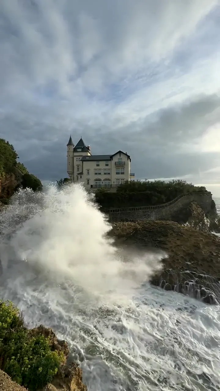 A château on the cliffs at Biarritz as a wave breaks below