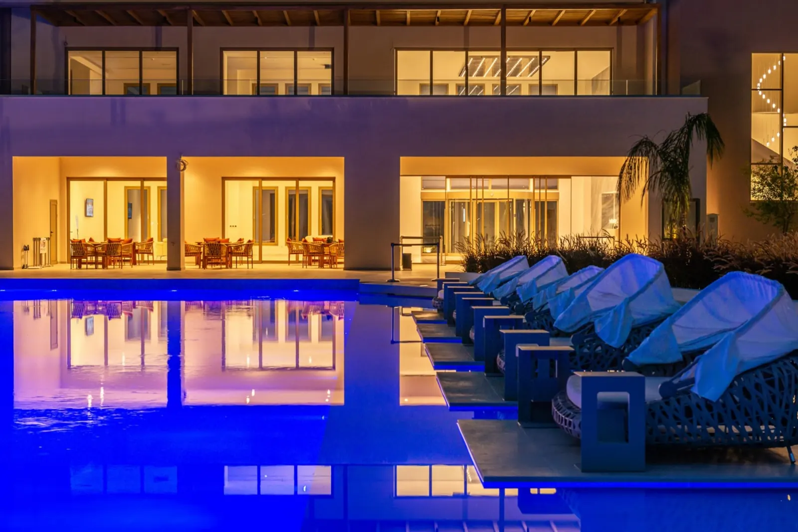 The main pool lit at night with the main building behind